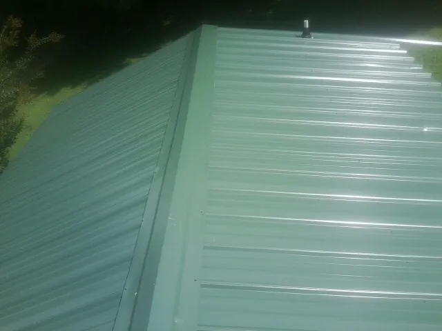 New green metal panels meeting at the ridge of a roof — Flat Roof Repair work by our crew in Ocean Grove