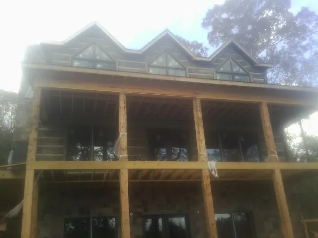 Dormers and porch framing on a large log home under construction — Roof Coating work by our crew in Ocean Grove