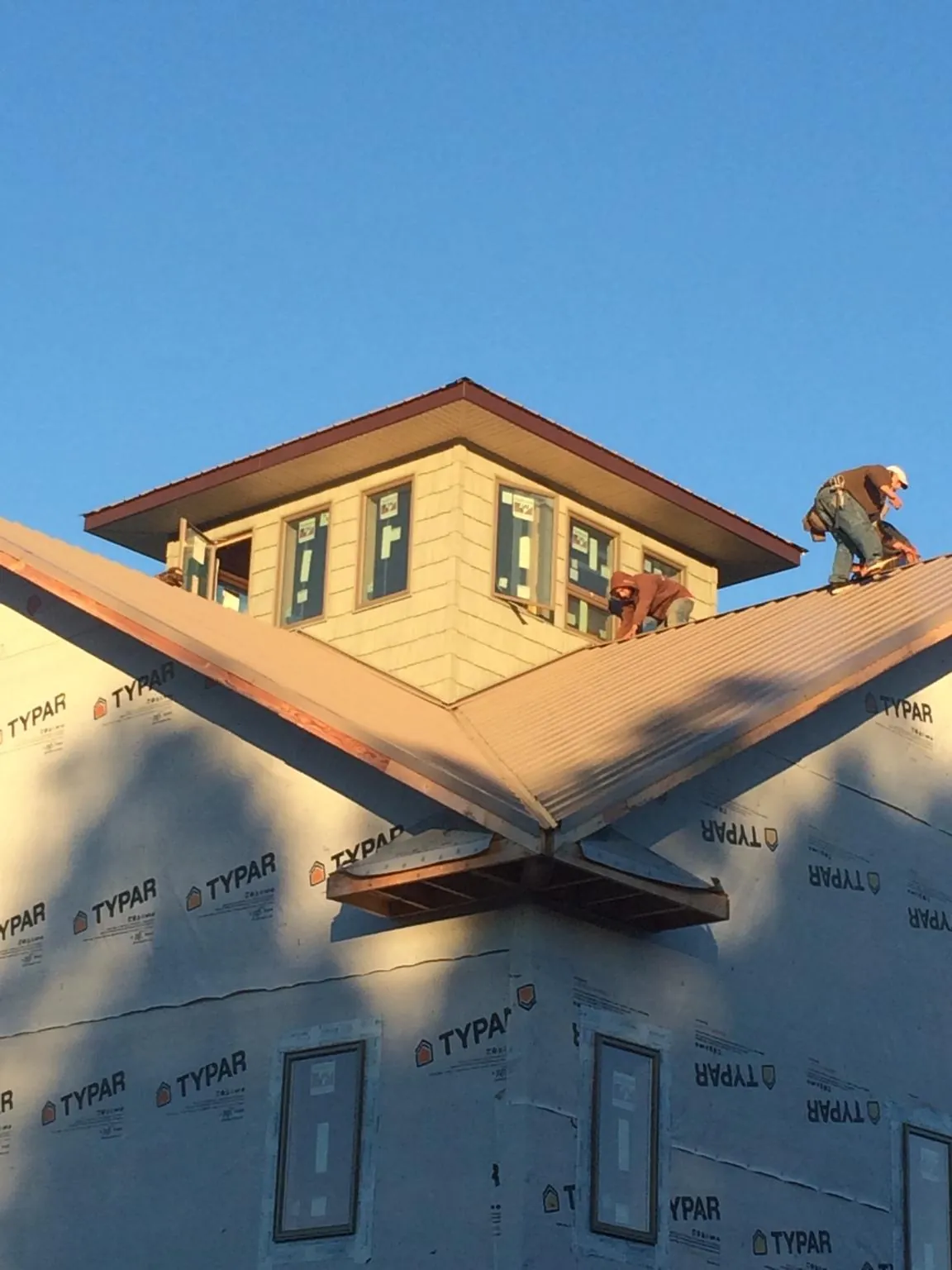 Roofers working around a rooftop cupola on a new metal roof at sunset — Roof Waterproofing in Ocean Grove by Roofing Brothers